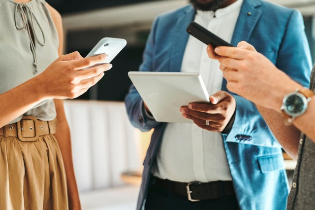 An image of three people holding electronics 