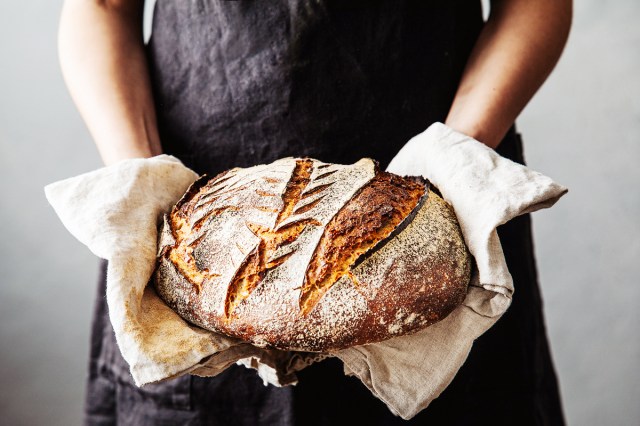 An image of a woman holding a circular loaf of bread