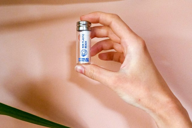 An image of a person holding white and blue labeled bottle of floss