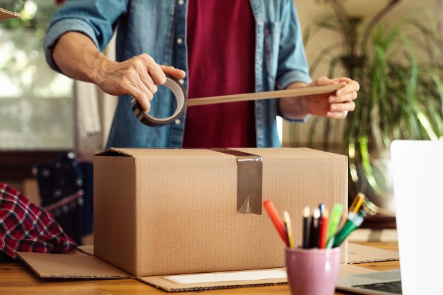 An image of a man taping a cardboard box