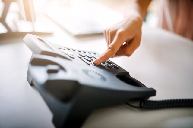 An image of a finger pressing a button on a large black phone