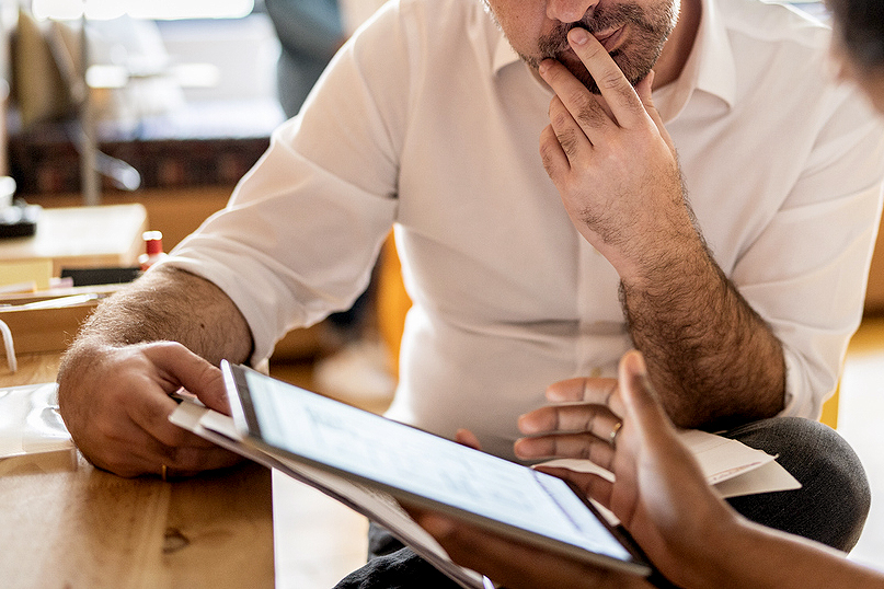 An image of a man looking at a digital tablet that a colleague is showing at work