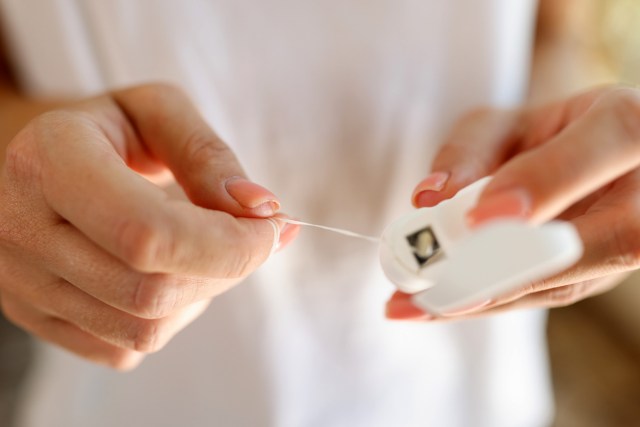 An image of a person pulling floss from a canister