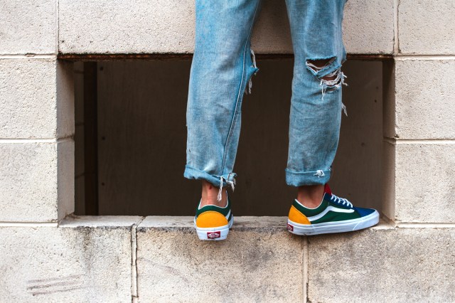 An image of a person wearing ripped jeans standing on a concrete wall