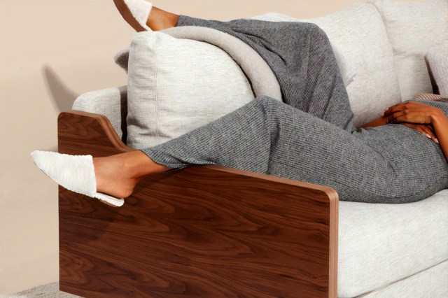 An image of a woman lying on a white sofa with wooden sides