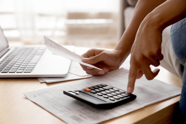 An image of a person holding paper bills using calculator