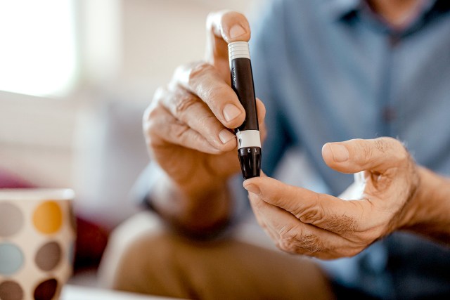 An image of a man pricking himself with a black needle