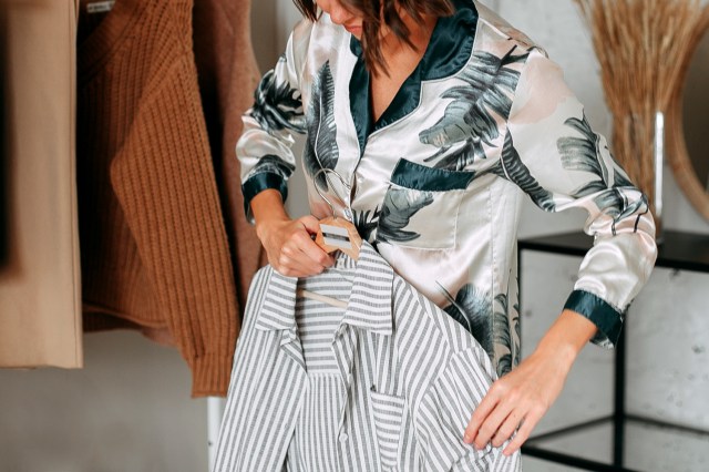 An image of a woman holding a shirt against herself in a store