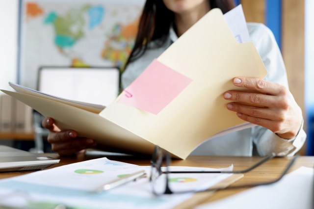 An image of a woman holding a manila folder