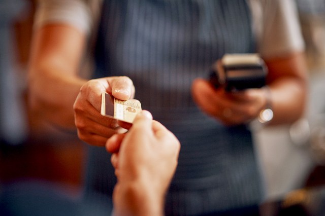 An image of a person handing a credit card to another person