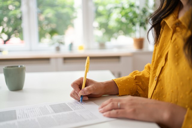 An image of a woman writing on a document