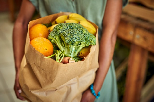 An image of a woman holding a paper bag of groceries