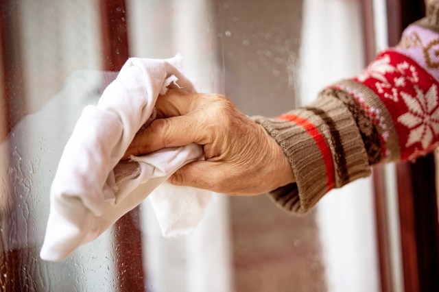 An image of a person cleaning a window with a white rag