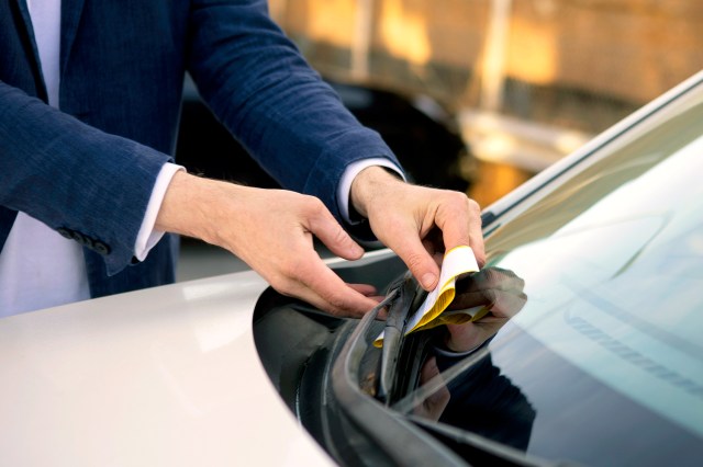 An image of a man taking a parking ticket off a car