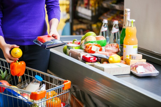 An image of a person putting groceries on a register belt