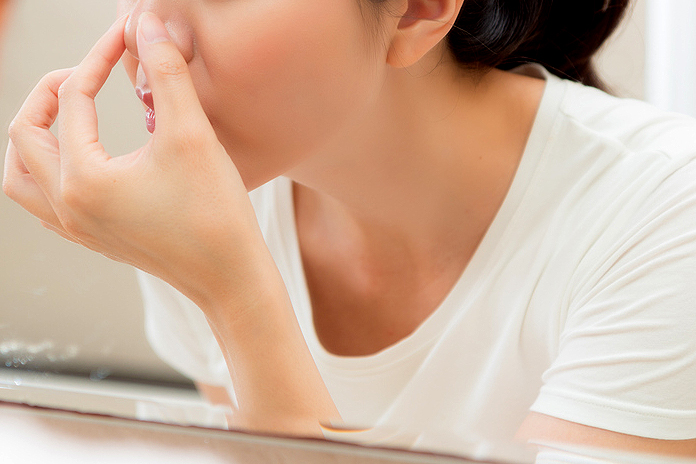 An image of a woman holding her nose