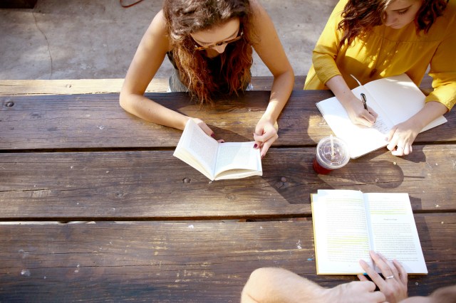 An image of three women reading at a wooden table