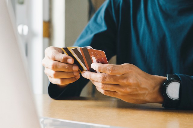 An image of a man holding three credit cards