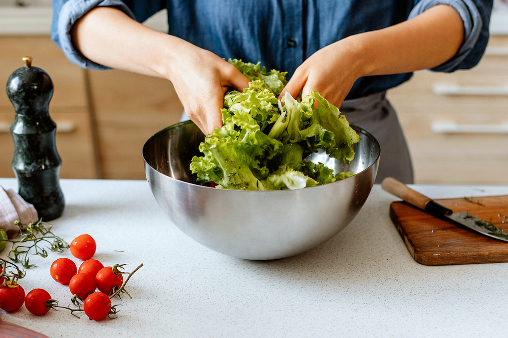 An image of a person tossing a salad with their hands