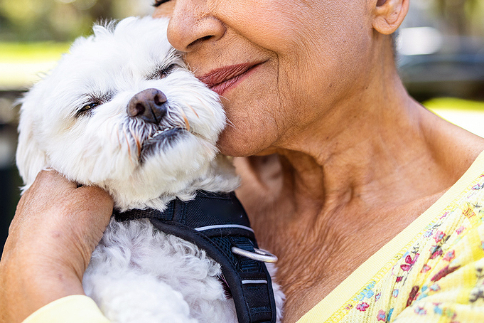 An image of a woman snuggling a small white dog