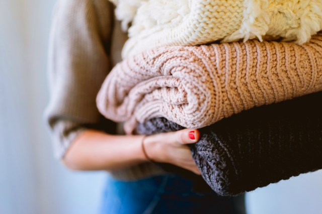 Person carrying a stack of clothing