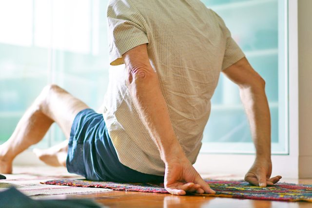 Person sitting on a rug with his arms behind him