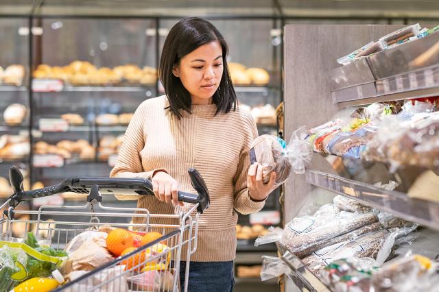 Woman at grocery store looking at a loaf of bread