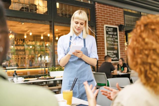 Waiter standing table side, taking orders on a notepad