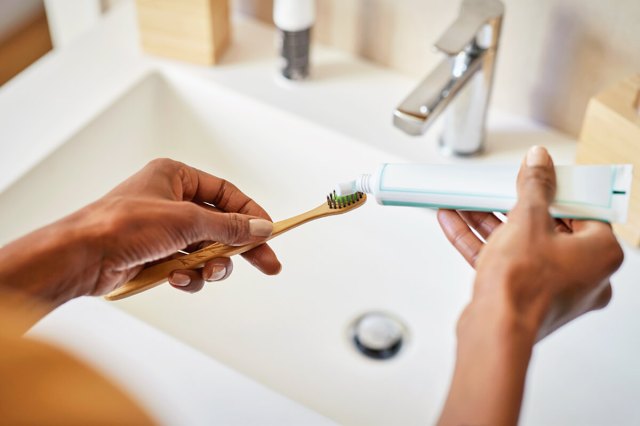 Person putting toothpaste on a toothbrush