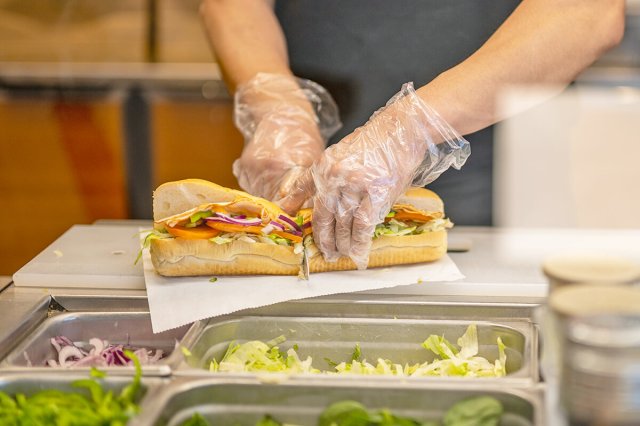 Restaurant worker cutting a hoagie in half