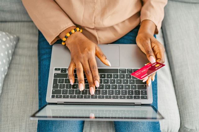 Woman typing on her laptop while looking at a credit card