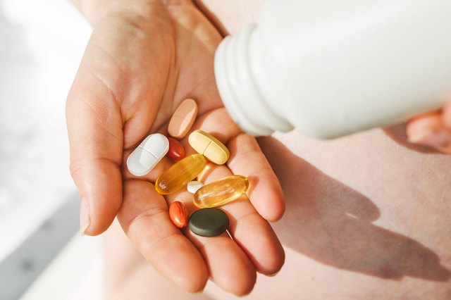 Person holding multiple vitamin pills in their palm