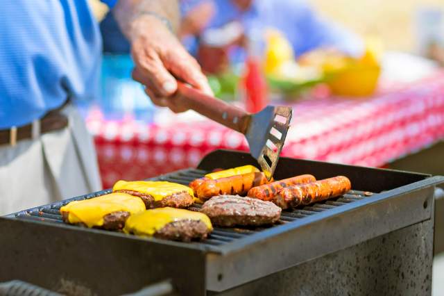 Person grilling cheeseburgers and hot dogs