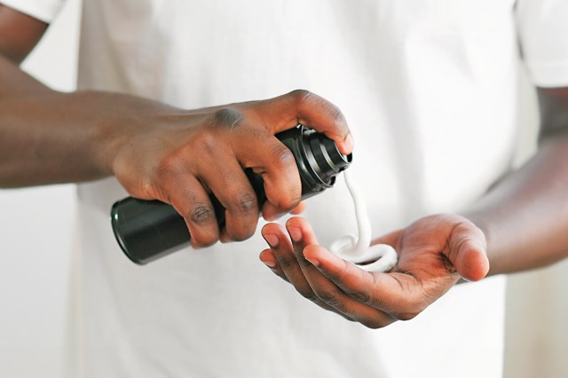 Man dispensing shaving cream from canister into his palm