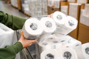 Person putting rolls of paper towels in a grocery cart