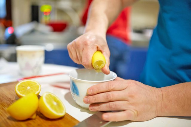 Person squeezing a lemon over a bowl