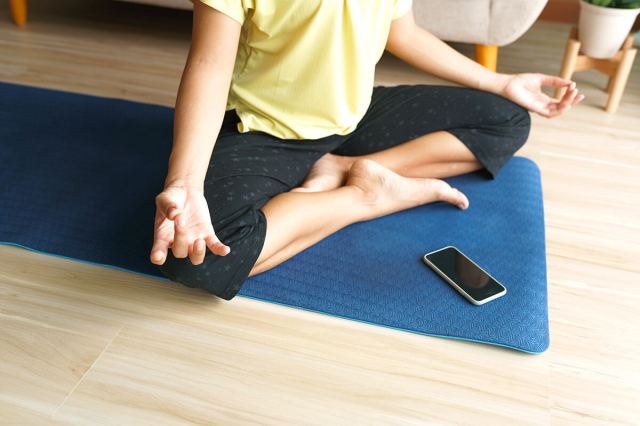 Person doing yoga with their phone on their mat