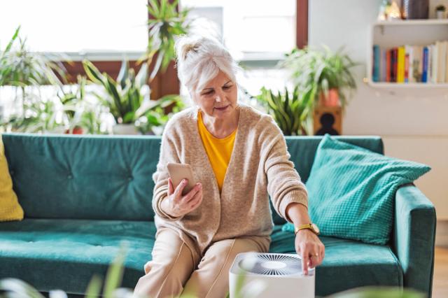 Older woman turning on a small air purifier