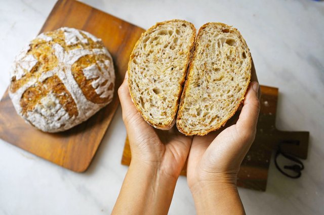 Person holding a loaf of bread that's been sliced in half